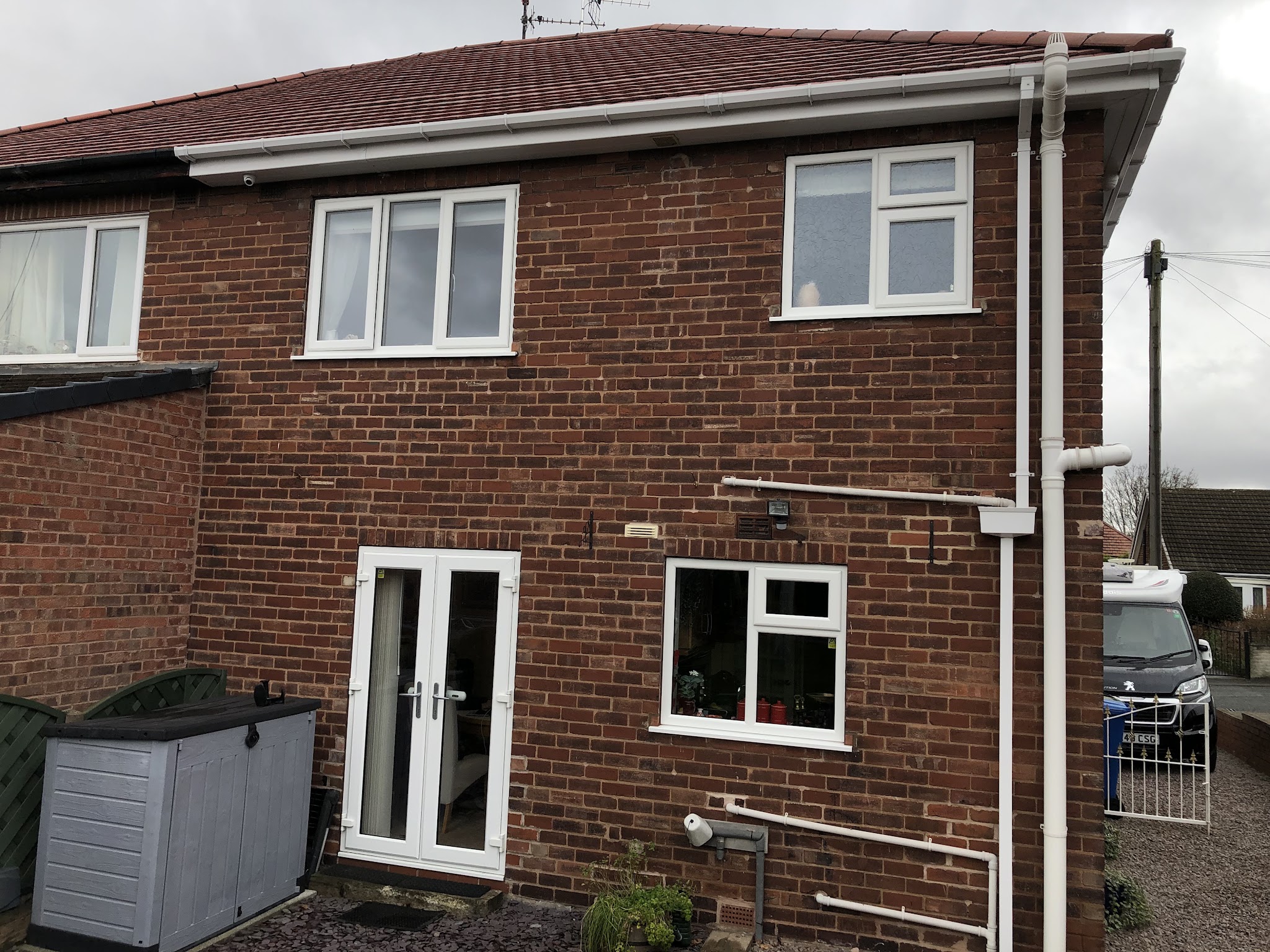 Back of a red brick house with new white windows and white French doors