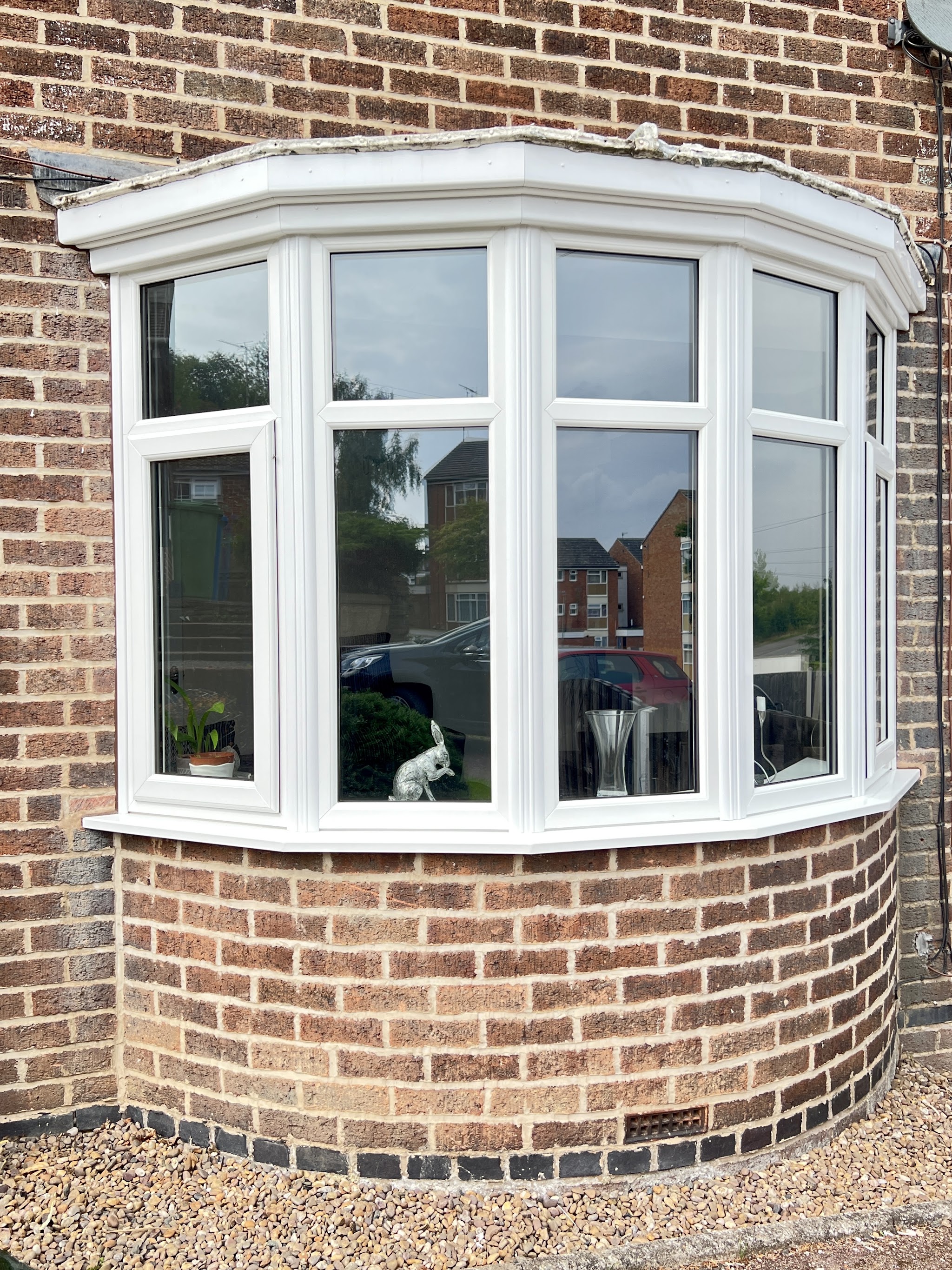 White uPVC bay window fitted into a curved red brick bay