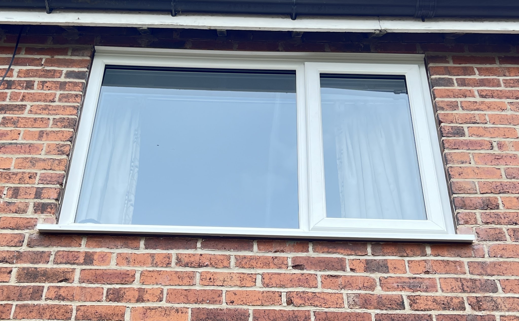 Wide white uPVC window set into red brickwork